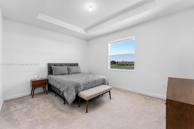 bedroom featuring baseboards, a tray ceiling, and light colored carpet