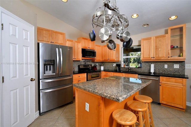 kitchen featuring appliances with stainless steel finishes, a kitchen island, tasteful backsplash, and light tile patterned floors