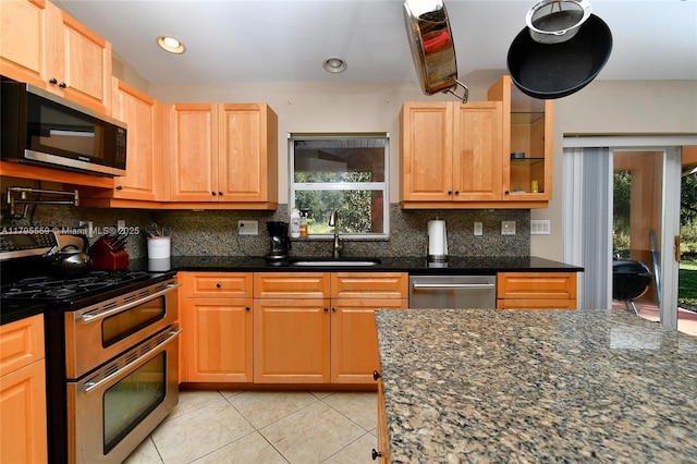 kitchen featuring light tile patterned floors, stainless steel appliances, a sink, and plenty of natural light