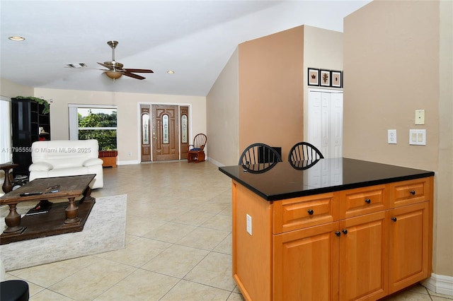 kitchen with a ceiling fan, dark countertops, visible vents, baseboards, and lofted ceiling