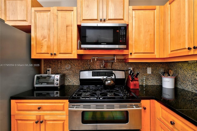kitchen with dark countertops, appliances with stainless steel finishes, decorative backsplash, and a toaster