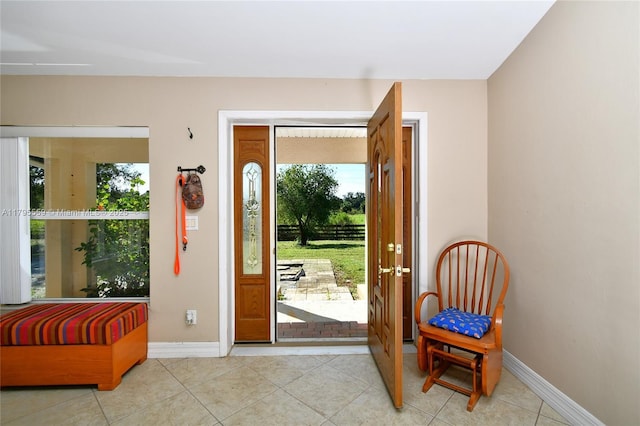 doorway to outside with baseboards, light tile patterned floors, and plenty of natural light
