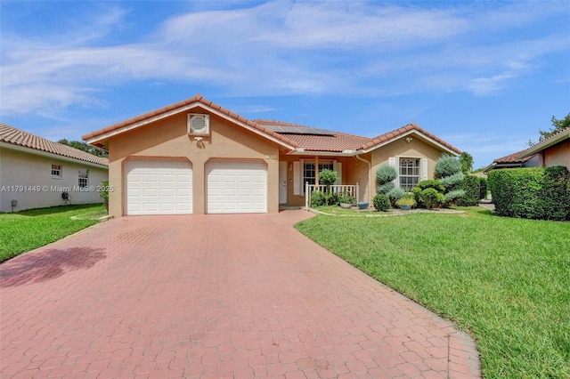 view of front of property with an attached garage, stucco siding, a front yard, solar panels, and decorative driveway