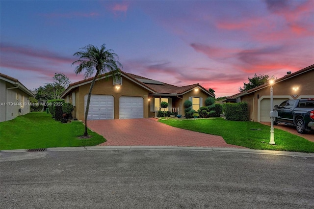 ranch-style house with a garage, roof mounted solar panels, decorative driveway, and a front yard