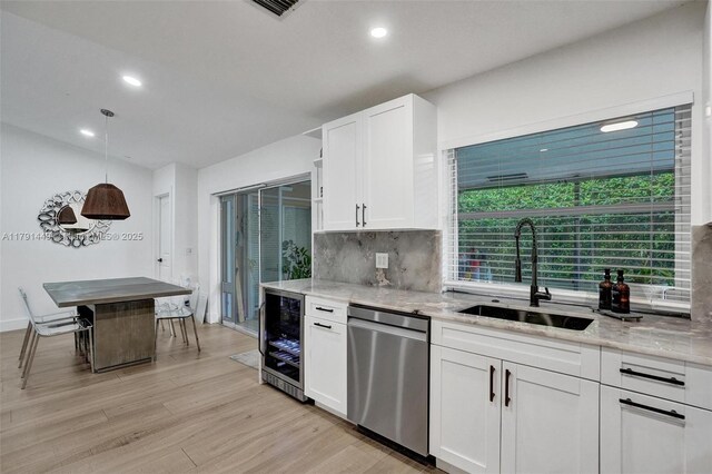 kitchen featuring tasteful backsplash, light wood-type flooring, dishwasher, white cabinets, and wine cooler