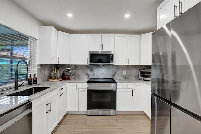 kitchen with decorative backsplash, stainless steel appliances, white cabinetry, and a sink