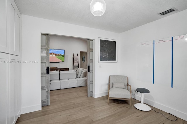 living area with baseboards, visible vents, and light wood finished floors