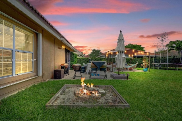 view of yard featuring a trampoline, a fire pit, a patio area, and fence