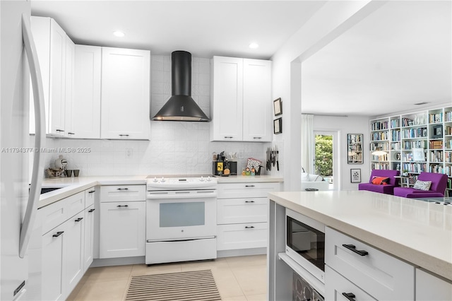 kitchen featuring white appliances, backsplash, white cabinetry, and wall chimney range hood