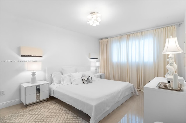 bedroom featuring baseboards, a notable chandelier, and light tile patterned floors