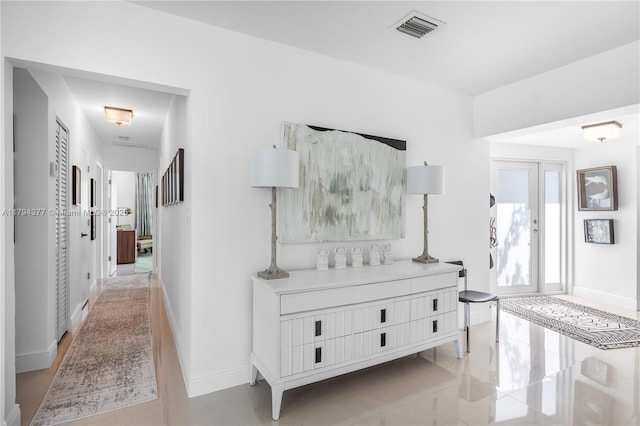 corridor featuring light tile patterned flooring, baseboards, and visible vents