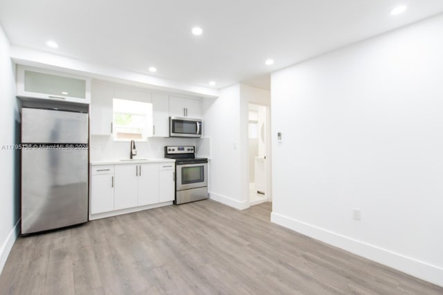 kitchen featuring a sink, baseboards, white cabinets, and stainless steel appliances