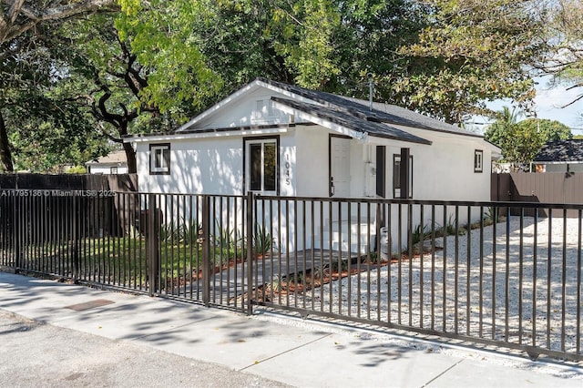 view of front facade with a gate, a fenced front yard, and stucco siding