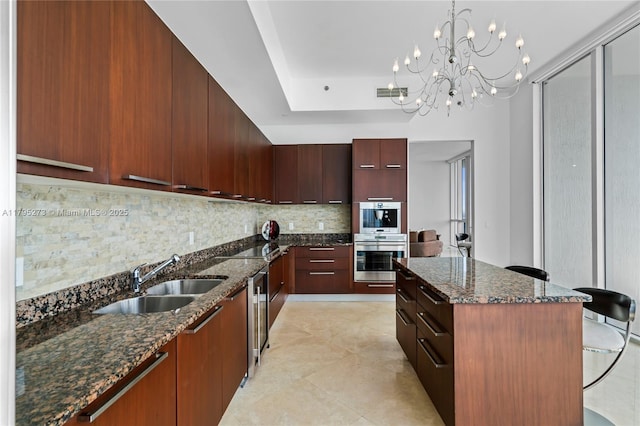 kitchen featuring a notable chandelier, a sink, backsplash, visible vents, and modern cabinets