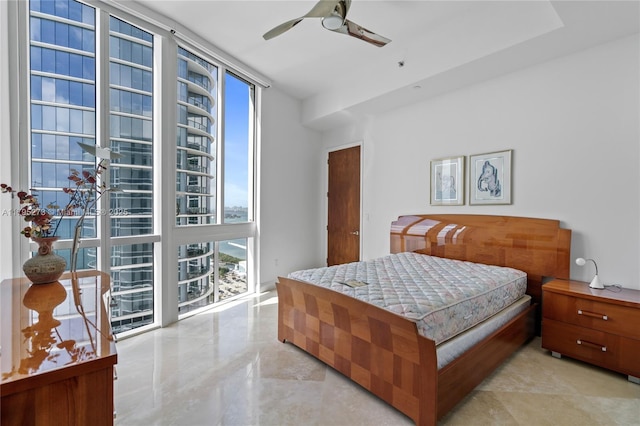 bedroom featuring a ceiling fan, a wall of windows, and multiple windows