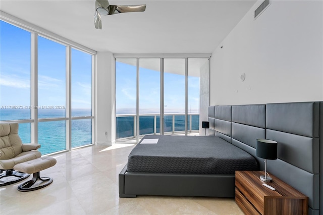 bedroom featuring visible vents, a water view, multiple windows, and a wall of windows