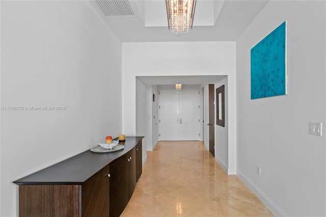 corridor with visible vents, marble finish floor, and a chandelier