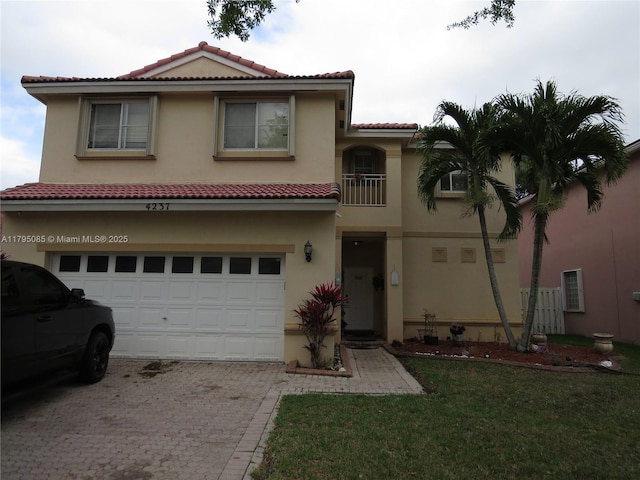 mediterranean / spanish home featuring a garage, stucco siding, driveway, and a tile roof