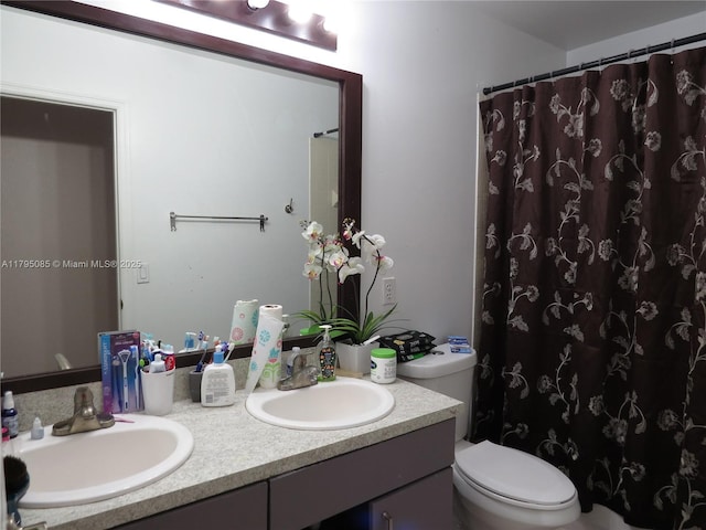 full bathroom featuring double vanity, toilet, curtained shower, and a sink