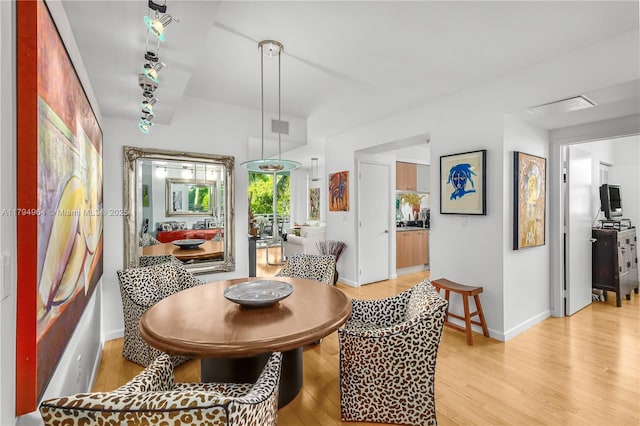 dining space with light wood-type flooring and baseboards
