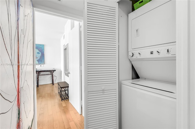 laundry room featuring laundry area, stacked washing maching and dryer, and light wood-style floors
