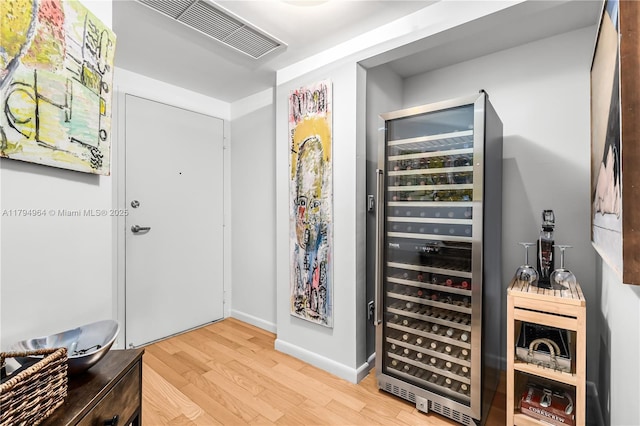 interior space featuring beverage cooler, baseboards, wood finished floors, and visible vents