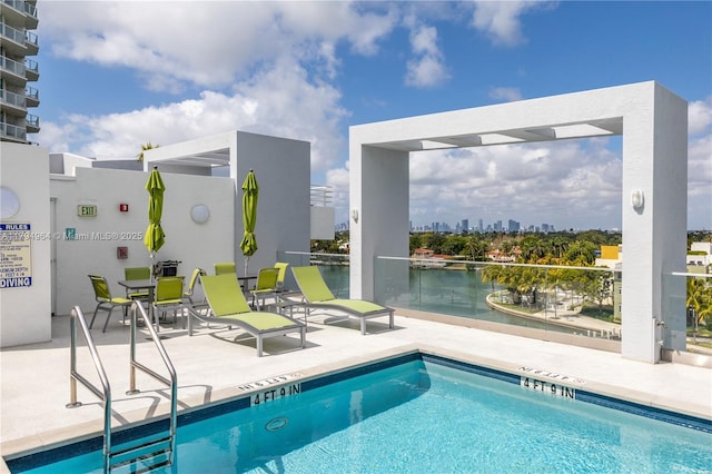 community pool with a view of city, a water view, and a patio
