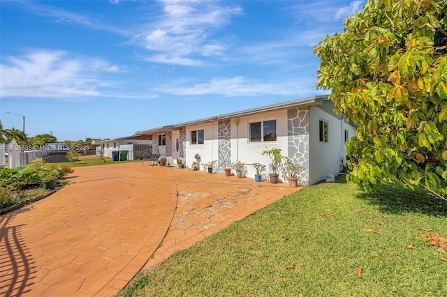 ranch-style house featuring stucco siding, fence, a patio area, and a front lawn
