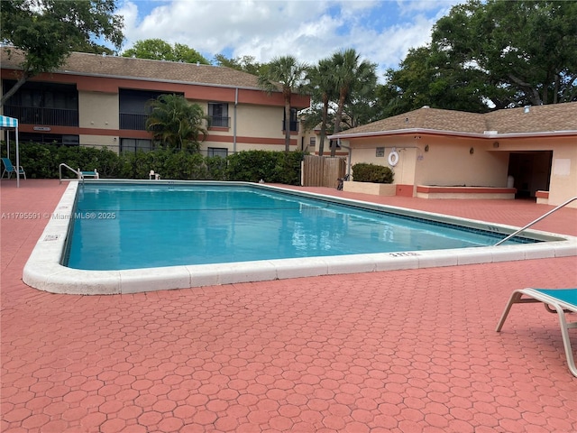 pool with a patio area and fence
