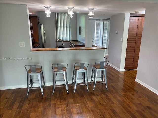 4133 S Carambola Cir S Unit G203, Coconut Creek, FL 33066 - kitchen featuring freestanding refrigerator, a chandelier, a sink, a kitchen breakfast bar, and baseboards