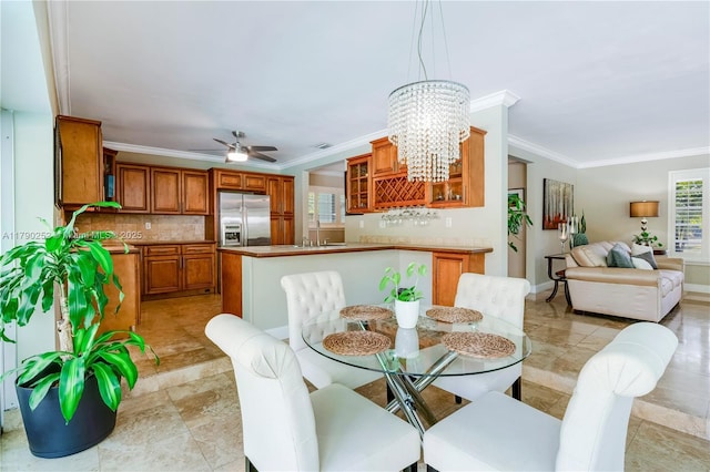 dining area featuring crown molding, baseboards, and ceiling fan with notable chandelier