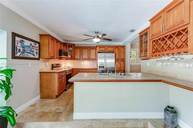 kitchen featuring backsplash, brown cabinets, a sink, a peninsula, and stainless steel appliances