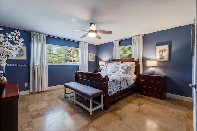 bedroom with baseboards, stone finish floor, and a ceiling fan