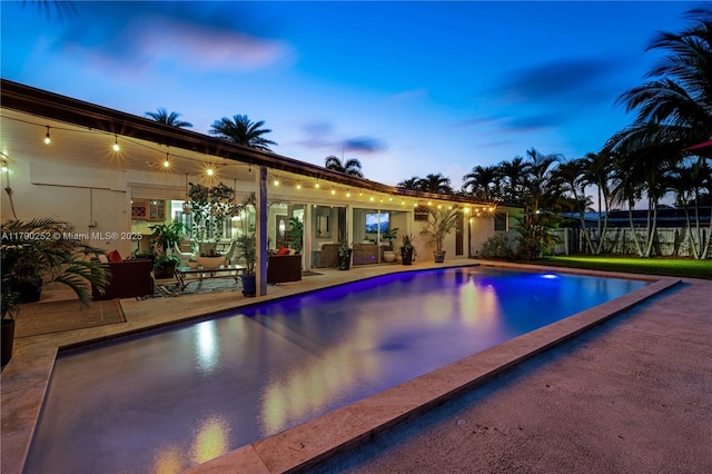 pool at dusk featuring a patio and an outdoor pool