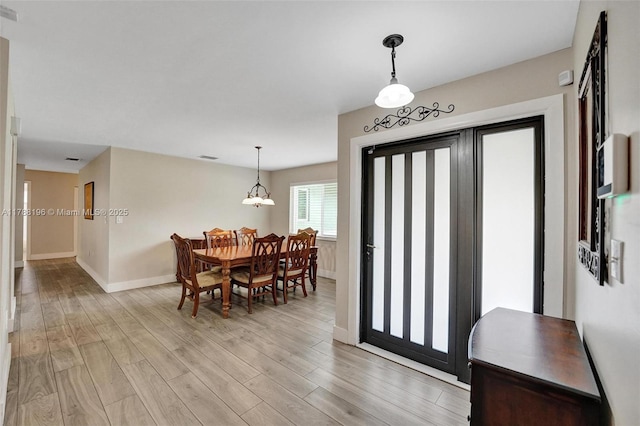 dining space with baseboards and light wood-type flooring