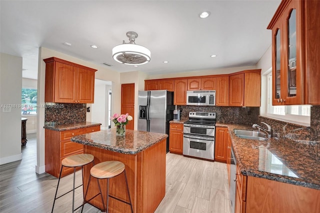 kitchen featuring a sink, stainless steel appliances, backsplash, a kitchen island, and glass insert cabinets