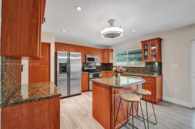 kitchen featuring backsplash, stainless steel appliances, light wood-style flooring, and a breakfast bar area