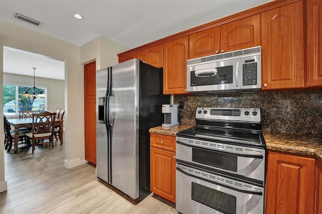kitchen featuring brown cabinets, stainless steel appliances, visible vents, and tasteful backsplash