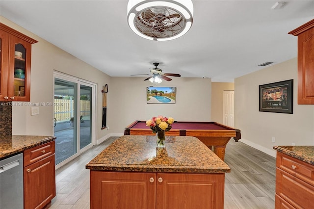 kitchen featuring light wood-style floors, stainless steel dishwasher, visible vents, a kitchen island, and glass insert cabinets