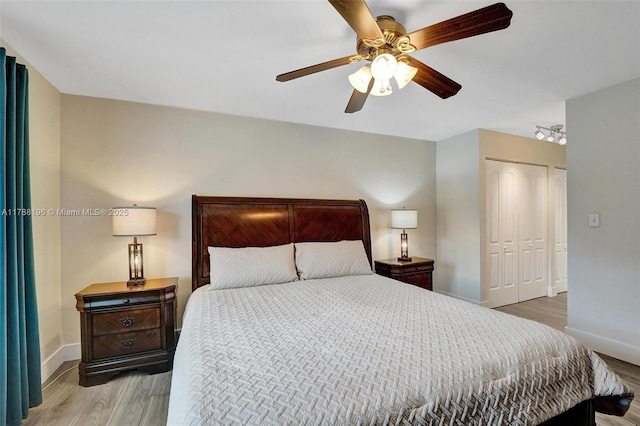 bedroom featuring light wood-type flooring, baseboards, ceiling fan, and a closet