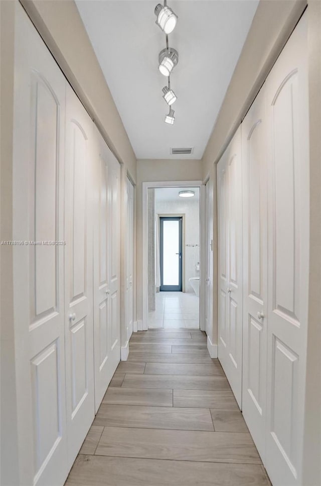 hallway featuring baseboards, visible vents, and light wood-style floors