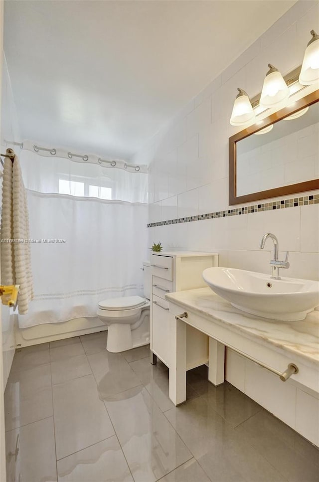 bathroom with vanity, toilet, tile walls, and shower / tub combo