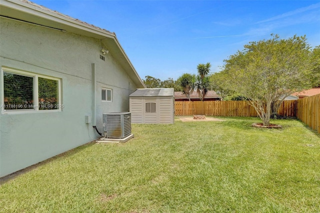 view of yard featuring a fenced backyard, a storage unit, central AC unit, and an outbuilding