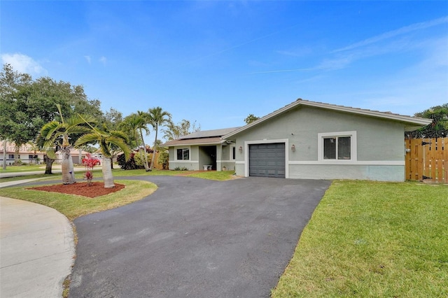 view of front of house with a garage, fence, roof mounted solar panels, aphalt driveway, and a front lawn
