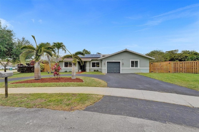 single story home with driveway, roof mounted solar panels, a front lawn, an attached garage, and stucco siding