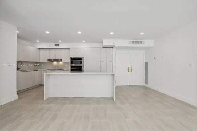 kitchen featuring stainless steel double oven, visible vents, modern cabinets, light countertops, and recessed lighting