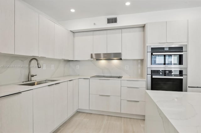 kitchen featuring double oven, visible vents, modern cabinets, and a sink