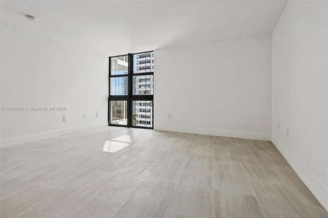 9 Island Ave Unit 1209, Miami Beach, FL 33139 - spare room with a wall of windows, light wood finished floors, baseboards, and a smoke detector