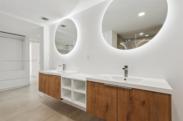 full bathroom featuring double vanity, visible vents, wood finished floors, and a sink