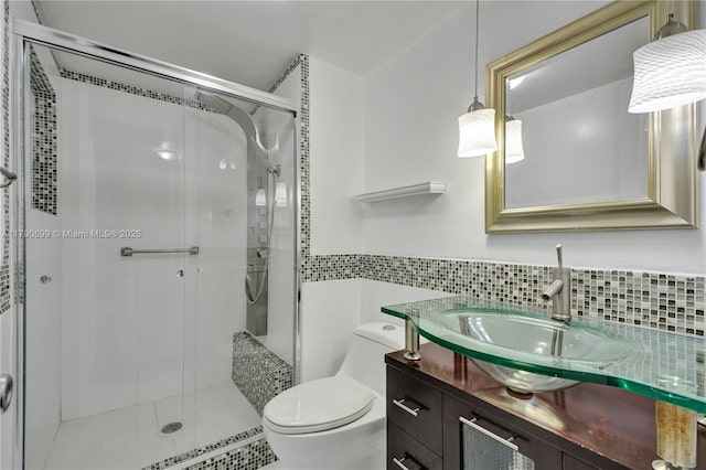 full bath with vanity, a shower stall, toilet, and tile walls